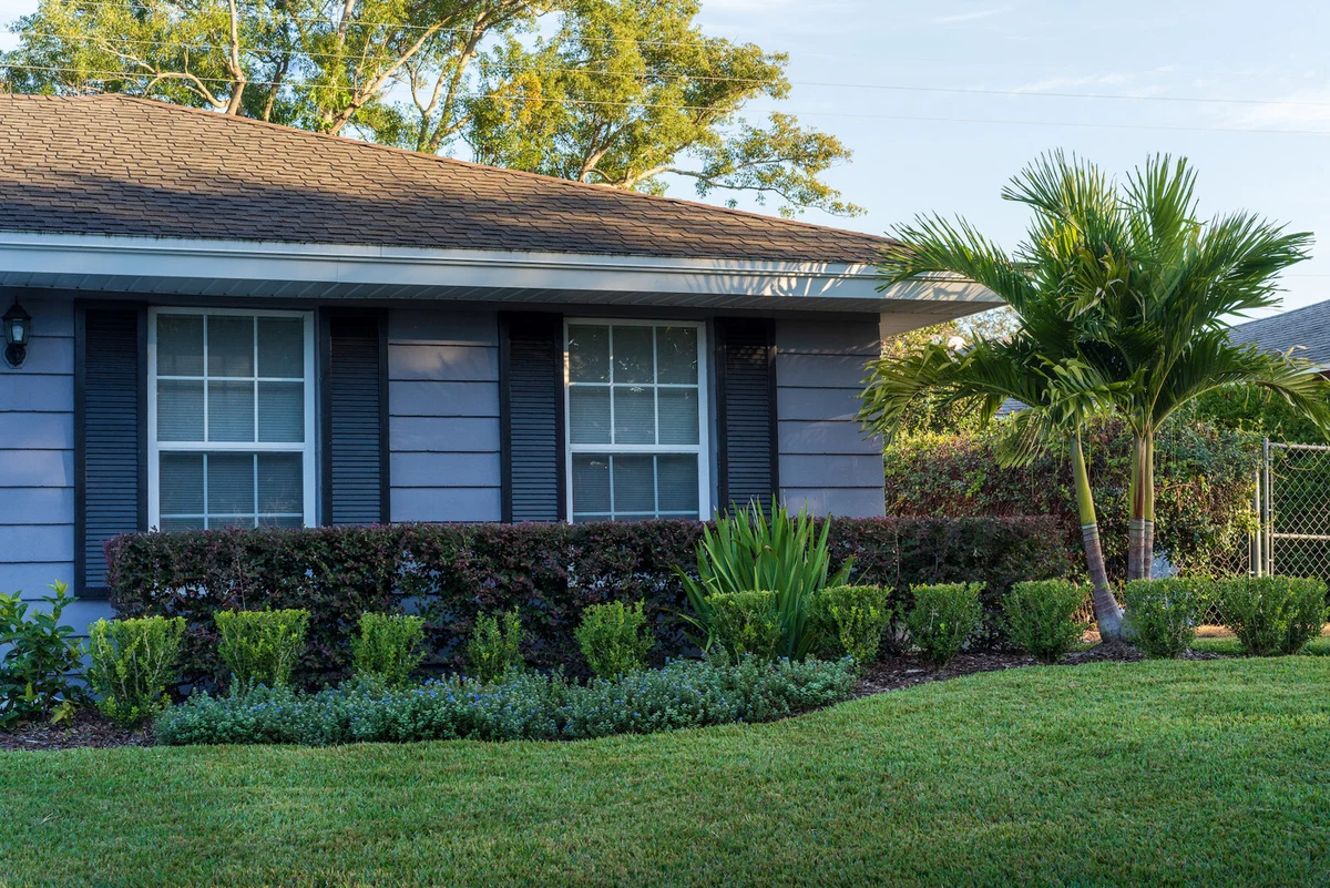 A Florida home framed by renewed layered flower beds and palms