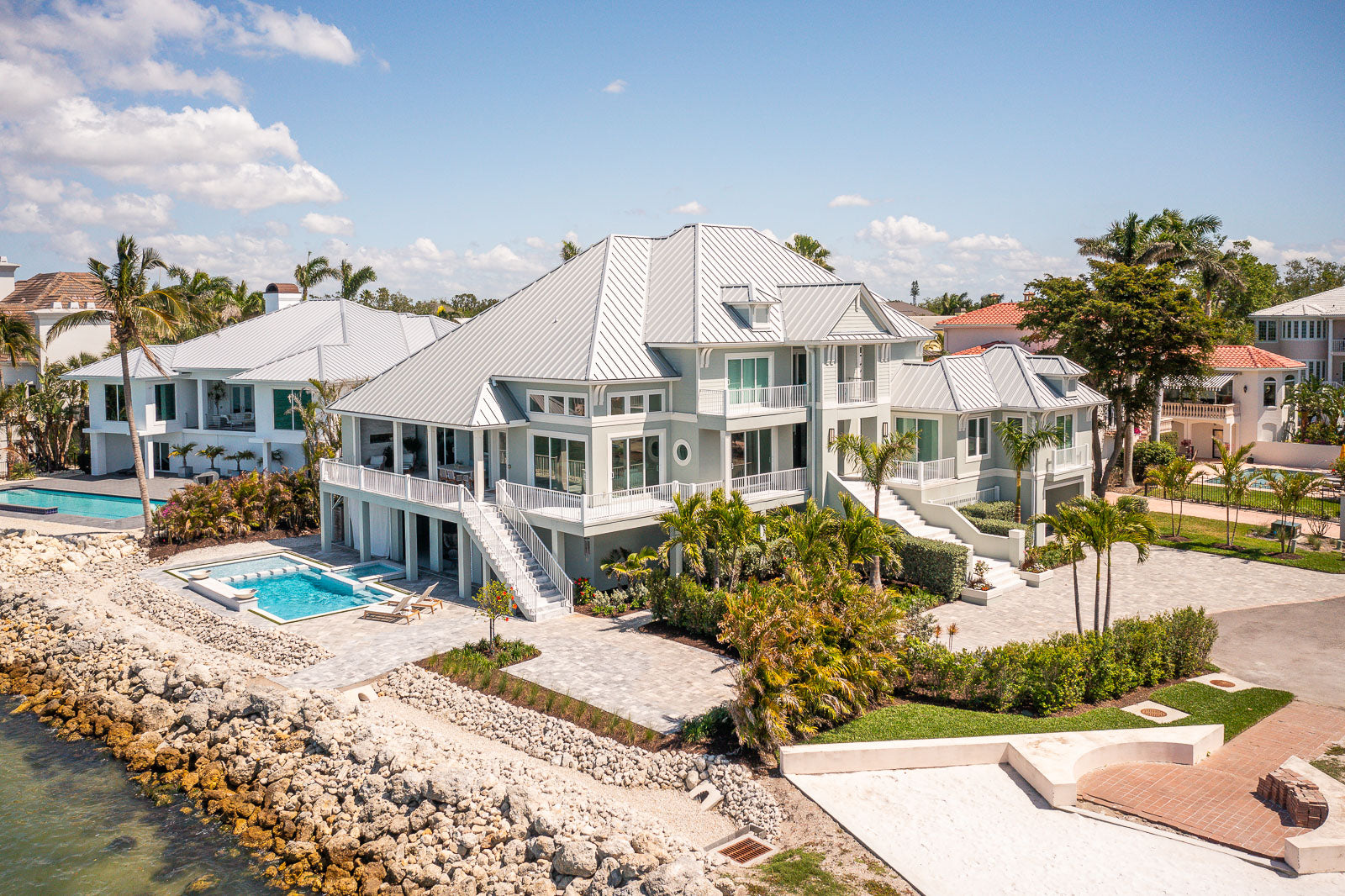 Aerial view of waterfront landscaping with a pool and paver patio