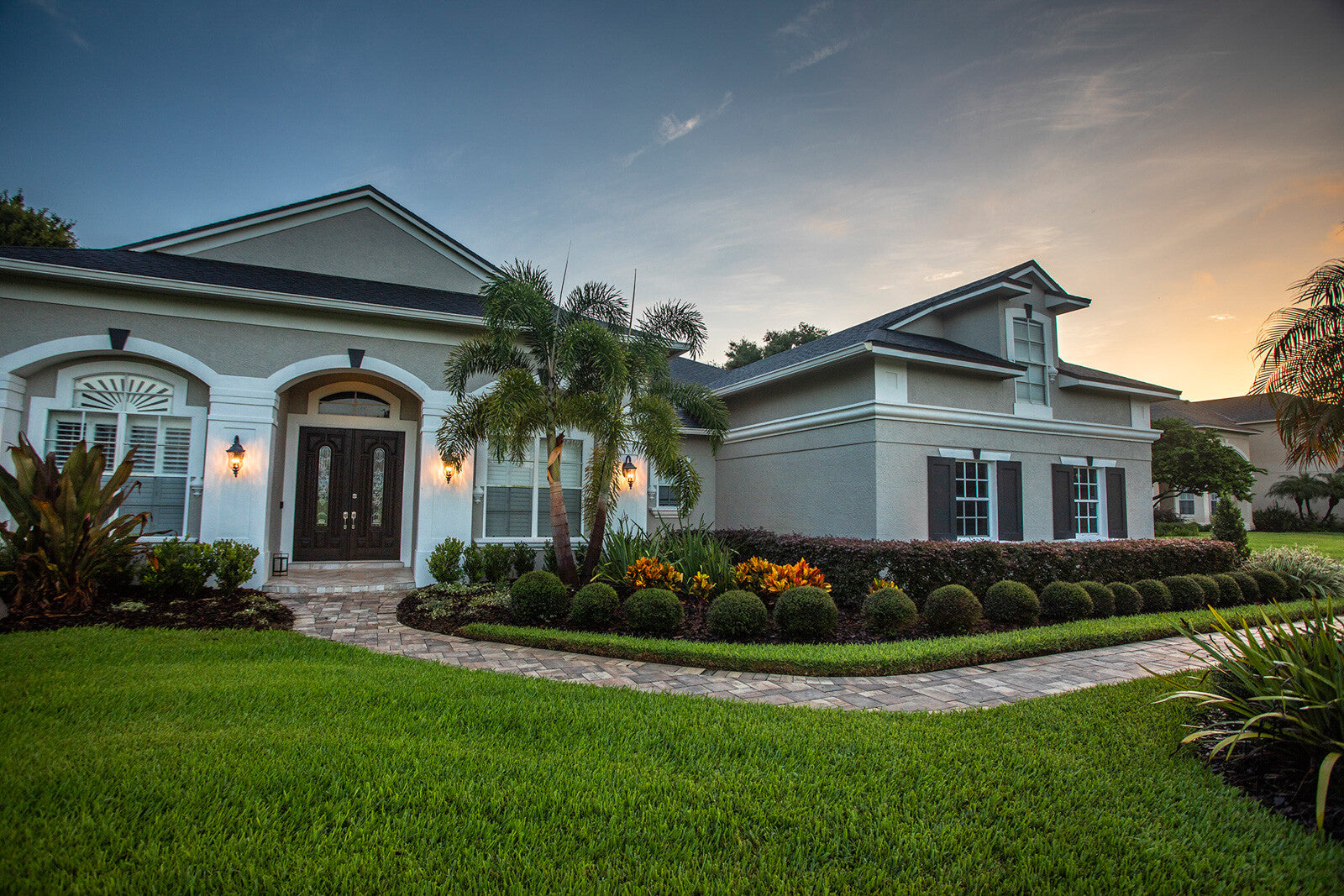 Florida-style home with palm trees and manicured landscape beds at dusk