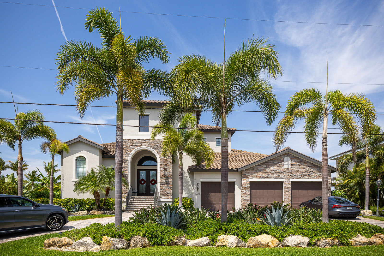 Front yard landscape design with palms and natural boulders